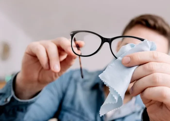 hombre limpiando las gafas de ver con una gamuza