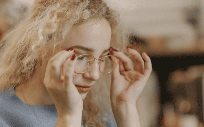 Primer plano de una mujer con vista cansada ajustándose las gafas de soloptical